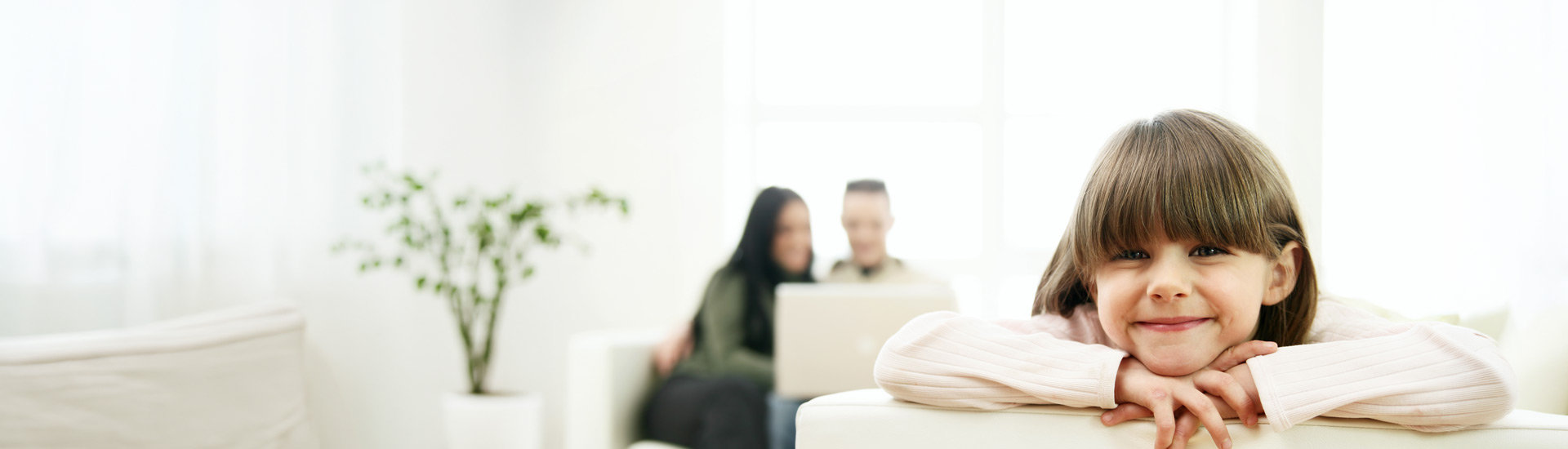 Glückliches Mädchen auf dem Sofa, Eltern am Laptop